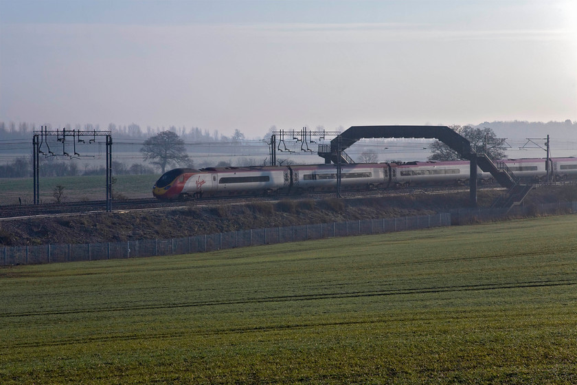 Class 390, VT 07.35 London Euston-Manchester Piccadilly (1H62), Blisworth 
 By turning the camera slightly further to the east and the rising sun the lighting of the photograph at Blisworth in the Weedon loop near to Northamptonchanges completely. An unidentified Class 390 heads north with the 1H62 07.35 Euston to Manchester service. 
 Keywords: Class 390 07.35 London Euston-Manchester Piccadilly 1H62 Blisworth Virgin Trains Pendolino