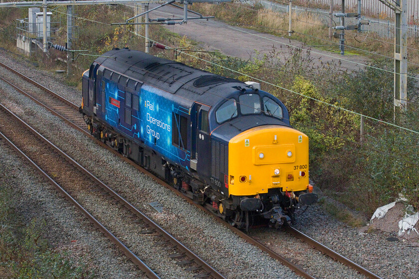 37800, 12.25 Derby RTC-Wembley Yard (0H72, 20L), site of Roade station 
 Another Rail Operations Group Class 37 light engine passes Roade. Having seen 37884 'Cepheus' heading north yesterday today it's 37800 'Cassiopeia' turn going south today. Catching some welcome afternoon sunshine the 0H72 12.25 Derby RTC to Wembley Yard was working hard before passing Roade with it engine audible some distance away. However, by the time it passed here, the engine had been notched right back. 
 Keywords: 37800 12.25 Derby RTC-Wembley Yard 0H72 site of Roade station ROG Rail Operations Group Cassiopeia