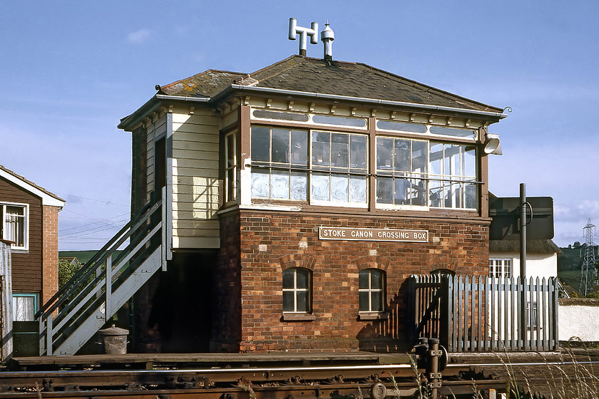 Stoke Canon Crossing signal box (B&ER,1876) 
 Stoke Canon Crossing signal box was a small affair built very early in 1876 by the Bristol and Exeter Railway to a design by Saxby and Farmer. It was unusual in having a row of toplight windows. It is seen here still bearing its GWR cast plate. Note the ground signal in the foreground protecting the cross-overs. At the time of writing in 2019, the box still stands but looks very sorry for itself but as the last surviving Bristol and Exeter signal box it is grade II listed by Historic England.... see..... https://historicengland.org.uk/listing/the-list/list-entry/1262013 
 Keywords: Stoke Canon Crossing signal box