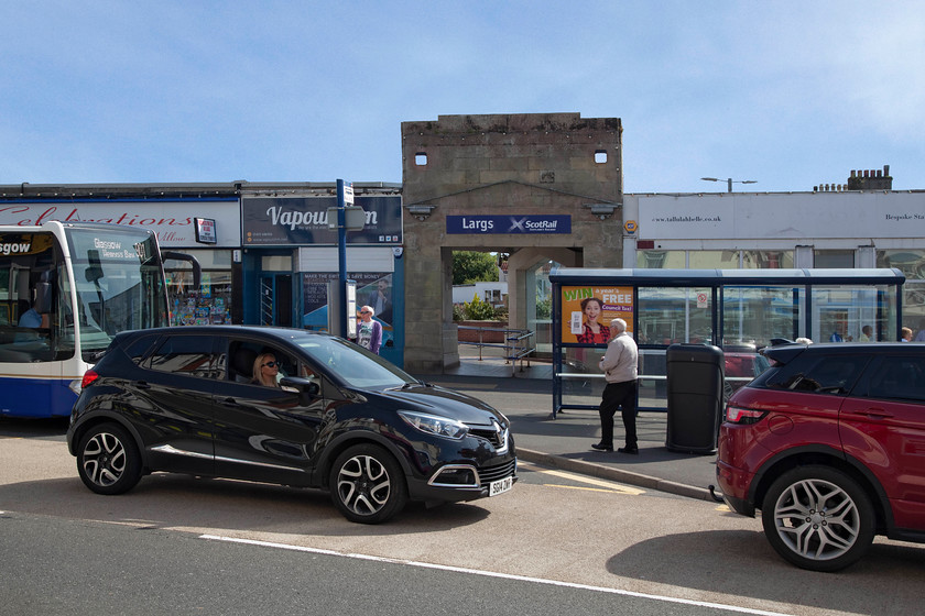 Frontage, Largs station 
 An unusual and somewhat cluttered view of the frontage of Largs station. However, I have a reason for this particular view. I took a very similar view during my 1984 Railrover. The shops are different now the vaping shop used to be called The Tartan Shop. The cars now are now a Renault Captur and a Range Rover Evoque, back in 1984 it was and Ford Escort XR3 and a Renault 9. However, the scene is essentially the same. Behind the frontage, Largs station is very different, with only two platforms and now structures to speak of. The shop to the right was completely destroyed in July 1995 when 318254 over-ran the buffers and careered on through the building ending up in the street. 
 Keywords: Largs station