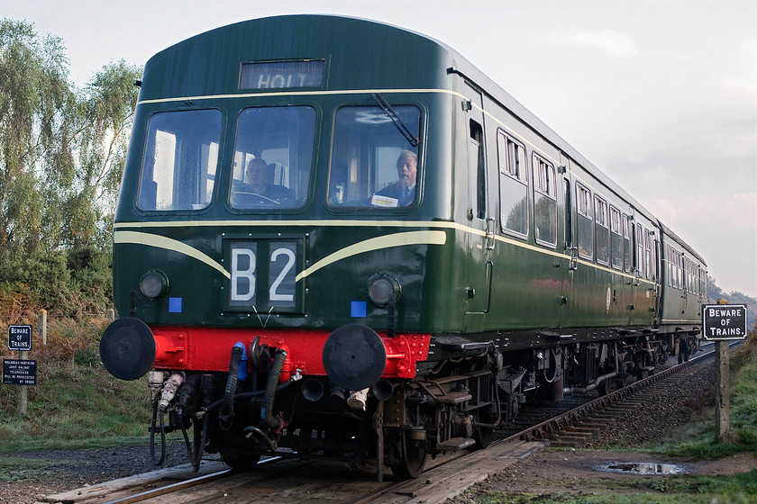 M51192 & M56352, 09.45 Sheringham-Holt, Kelling Heath 
 After a recent restoration, M51192 looks superb in its British Railways green livery with 'speed' whiskers. Attached to the rear is M56352 that remains in its rather faded un-restored livery. The class 101 is widely regarded as one of the most successful and enduring designs of of first generation DMUs. Built by Metro-Cammell in Birmingham between 1956 and 1959 they operated all over the country. When the last examples were withdrawn they were forty seven years old. The unit is seen passing Kelling Heath's footpath crossing with the 09.45 Sheringham to Holt service. 
 Keywords: M51192 M56352 09.45 Sheringham-Holt Kelling Heath