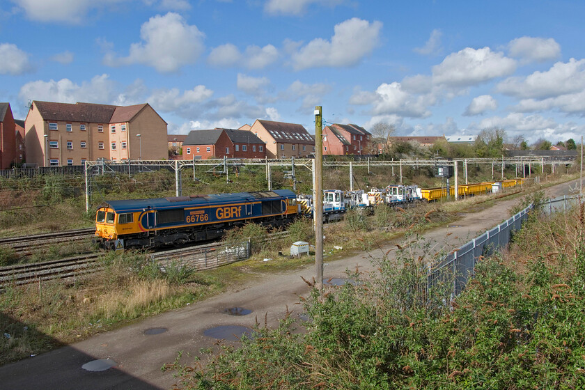 66766, engineering train in possession, site of Roade station 
 GBRf's 66766 'Gail Richardson' creeps along at the rear of an engineering train heading for the Sergo Logistics Park a short distance from this location in Roade. There was a full engineering possession over the long Easter weekend in order to complete the connection of the new logistics facility to the Northampton loop. This work has been going on for over a year now and I really am not too sure why the installation of two sets of facing points and the northern and southern end of the new lines has taken so long. This drawing out of jobs by Network Rail and its contractors seems to be the norm now.....comments welcome. 
 Keywords: 66766, engineering train in possession, site of Roade station GBRf Gail Richardson