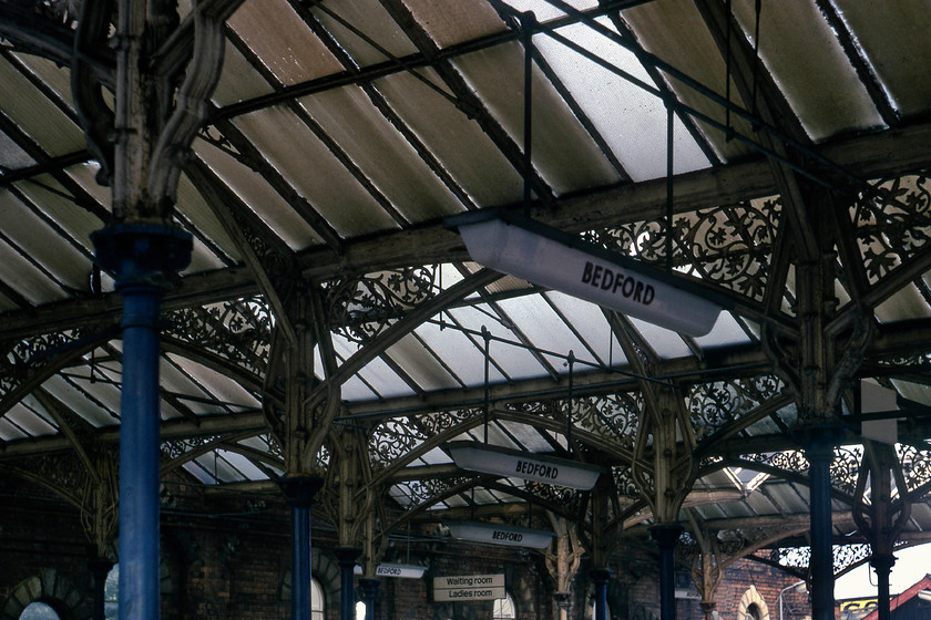 Roof details, Bedford Midland station (Closed October 1978) 
 We arrived at Bedford during a period of transition, but in true BR style, things were happening slowly! This is the remains of the former Bedford Midland station that had closed some ten months previously to be replaced by the new station a short distance north. However, despite this, the station was still standing and access was easily gained. As can be seen here, the signage was still present, this is somewhat of a surprise as I thought that it would have been purloined by locals and collectors? Notice the heavily polluted glazing fitted to the lovely wrought iron roof to a typical Midland design. 
 Keywords: Bedford Midland station