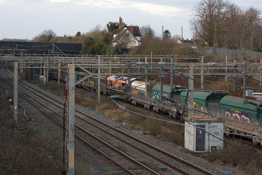 66413, 13.14 Wembley Reception-Tunstead Sidings (6H50, 102L), site of Roade station 
 A messy grab shot shows 66413 'Lest We Forget' in the middle of the 6H50 13.14 Wembley Reception to Tunstead Sidings empty stone train passing through Roade. I am not at all sure as to the circumstances of this event but it appears that two trains were joined making one jumbo one. 66622 was leading the train without any assistance as 66413 was switched off. If anybody can enlighten me as to why this course of events took place it would be appreciated. 
 Keywords: 66413 13.14 Wembley Reception-Tunstead Sidings 6H50 site of Roade station Lest We Forget