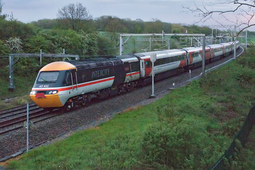 43102, EM 20.02 London St. Pancras-Leeds (1F70, 3E) 'the final HST service', Sharnbrook Road bridge 
 The last EVER HST working from London......

The end of a forty-five-year era takes place at Souldrop on the climb of Sharbrook bank as the final ever commercial HST heads north in absolutely awful lighting. 43102 'The Journey Shrinker' leads the 1F70 20.02 St. Pancras to Leeds with EMR celebrity 43274 bringing up the rear. The leading power car in its superb InterCity Swallow livery wears a headboard proclaiming 'LAST HST FROM LONDON' will go into preservation as part of the national collection with the stock, still wearing its Virgin East Coast/LNER paint scheme probably going for scrap sooner than later. I would not normally bother with a photograph in such awful lighting but the enormity of the event meant that it just had to be done! 
 Keywords: 43102 20.02 London St. Pancras-Leeds 1F70 the final HST service Sharnbrook Road bridge EMR HST East Midlands Railway The Journey Shrinker