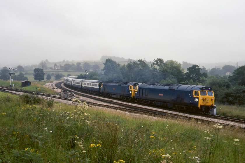 50001 & 50025, 16.45 Plymouth-London Paddington (1A57), Aller Junction 
 It's now late afternoon and the haze has been driven in from the coast - only a mile or so further inland it was clear with some brightening skies but not here at Aller Junction. Taken from the signalman's parking spot just behind the box 50001 'Dreadnought' and 50025 'Invincible' lead the 1A57 16.45 Plymouth to Paddington service. We never did establish why this was double-headed. It was before BR trialed the so-called 'super trains' that often saw two Class 50s working together, so perhaps it was due to a failure? To take the equivalent photograph today, I would need to be standing by the side of the very busy A380 dual carriageway taking my life into my hands in doing so! 
 Keywords: 50001 50025 16.45 Plymouth-London Paddington Aller Junction Dreadnought Invincible 1A57