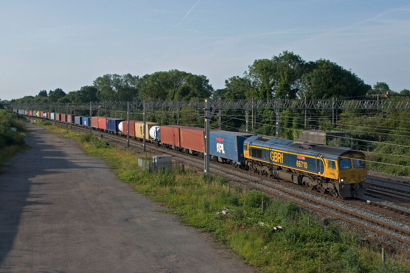 66710, 03.15 Felixstowe North-Trafford Park (4M18, 20E), site of Roade station 
 GBRf's 66710 'Phil Packer' leads the 03.15 Felixstowe to Trafford Park 'liner service past Roade. This 4M18 service runs six days per week always [assing this spot (if it's running to time that is!) at about 07.15. This bright and sunny start to the day did not last. Within an hour or so the clouds had gathered followed by some burst of very heavy rain. 
 Keywords: 66710 03.15 Felixstowe North-Trafford Park 4M18 site of Roade station GBRf Phil Packer