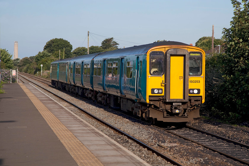 150253 & 143614, AW 07.42 Bridgend-Aberdare (2A12), Rhoose station 
 150253 and 143614 arrives at Rhoose station with 2A12, the 07.42 Bridgend to Aberdare morning commuter working. The station is a split platform affair that is a short distance from Cardiff International airport. The large chimney in the background belongs to Aberthaw power station. 
 Keywords: 150253 143614 07.42 Bridgend-Aberdare 2A12 Rhoose station