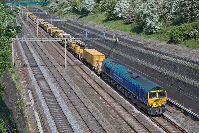 66623, 08.45 High Oaks Junction-Willesden Euroterminal (6Y15), Roade cutting 
 66623 'Bill Bolsover' leads the absolutely huge Network Rail 'drain train' through Roade cutting at almost walking pace! Assisting on the rear, out of sight due to the length of the train, is 66523. The so called 'drain train' is composed of high output ballast cleaner (HBOC) units that Network Rail has recently invested fifty million pounds in! This gargantuan train, running as 6Y15, left High Oaks Junction (Rugby) at 08.45 and is making its way very slowly to the Willesden Eurotunnel terminal. 
 Keywords: 66623 08.45 High Oaks Junction-Willesden Euroterminal 6Y15 Roade cutting Bill Bolsover