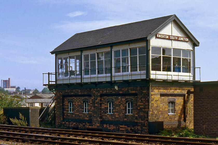 Knighton South Junction signal box (LMS, 1936) 
 Moving closer to Leicester city centre Knighton South Junction signal box is seen in the August sunshine. It was located adjacent to the up slow line at the point where the Midland route to Stenson Junction via Coalville left the MML. This line is still open today as a freight-only route but there are continual plans for it to reopen again for passenger use. The box is an LMS Type 11c design that opened in 1936 that replaced an 1890 box that was located where the relay room is seen to the right of the image. The new box was fitted with a sixty-lever frame. Notice the tall twin structures to the extreme left in this view, they are part of Leicester University located in Victoria Park. 
 Keywords: Knighton South Junction signal box LMS London Midland and Scottish Railway