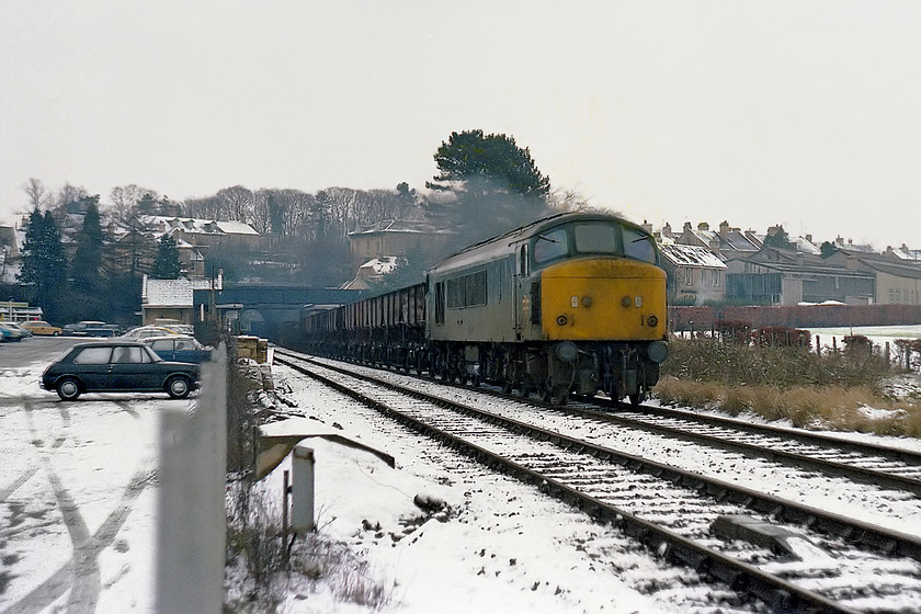 45007, down freight, Bradford-on-Avon station from station car park 
 Another unusual working was observed from the station car park at Bradford-on-Avon. 45007 leads a long freight of mixed empty wagons heading in the Bristol direction. Looking at the age and type of wagons I wonder if they had been selected for scrap and were making their final journey to the cutters? The Peak (ex. D119) lived on until 1988 after which it was cut up by MC Metals in Springburn. I bet that the rare two-door Morris 1100 in the station car park did not last that long before rusting into an oblivion! 
 Keywords: 45007 down freight Bradford-on-Avon station from station car park