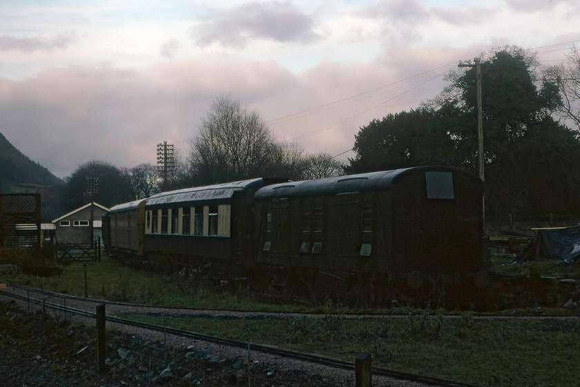 Preserved stock, Betws-y-Coed station 
 In the gloom at Betws-y-Coed station is some preserved stock owned by the Conwy Valley Railway Museum. They also operate a narrow gauge railway on their site that can be seen in the foreground. The stock seen is a Southern parcels van either 1070 or 407 and a Pullman coach 'Emerald' both of which are still there today some forty years on from this gloomy picture being taken. 
 Keywords: Preserved stock Betws-y-Coed station