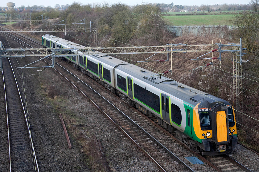 350116, LN 12.14 Birmingham New Street-London Euston (1Y40, 3E), Victoria Bridge 
 Still wearing its London Midland livery but now de-branded due to London Northwestern having taken over the franchise a couple of weeks earlier, 350116 passes Victoria Bridge just south of Roade with the 12.14 Birmingham New Street to Euston. One of Roade's water towers can be seen in this image, the other one is hidden behind the trees in the centre of the image. 
 Keywords: 350116 12.14 Birmingham New Street-London Euston 1Y40 Victoria Bridge