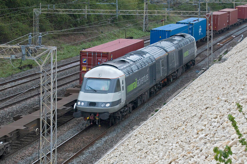 43468 & 43480, 11.54 Rugby-Willesden Yard (0Z45, 9L), Ashton Road bridge 
 Having seen the down working a little earlier 43468 now leads with 43480 trailing as the 0Z45 11.54 Rugby to Willesden Yard return test run seen passing Ashton Road bridge just south of Roade. They are passing the tail end of the slow-moving 07.50 Felixstowe North-Lawley Street Freightliner. The railadventure (sic) re-purposed HSTs are used for various stock moves, generally of new trains, around the country of which there seems to be plenty at the moment. Later in the day, having done a return London to Rugby run the pair headed north again to be stabled at Kings Norton to the south of Birmingham. Unfortunately, I was unable to see this third and final run due to being out for lunch with my wife but by then it was pouring with rain anyway! 
 Keywords: 43468 43480 11.54 Rugby-Willesden Yard 0Z45 Ashton Road bridge Rail Adventure HST