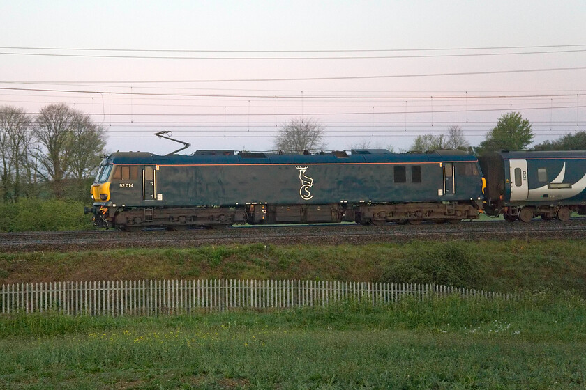 92014, CS 21.52 Glasgow Central-London Euston (1M11, 21E), between Roade & Ashton 
 Whilst I have plenty of photographs of the Highland sleeper service as it normally passes close to home at a fairly civilised time just before 07.00 the Lowland service has been captured much less often due to it passing around 05.50. On this particular morning the 1M11 21.52 Glasgow Central to Euston (via a reversal at Edinburgh) is seen passing just south of Roade running some twenty minutes early lead by 92014 that is doing its best to blend its Caledonian Sleeper livery into the half-lit lush green spring countryside! 
 Keywords: 92014 21.52 Glasgow Central-London Euston 1M11 between Roade & Ashton Caledonian Sleeper