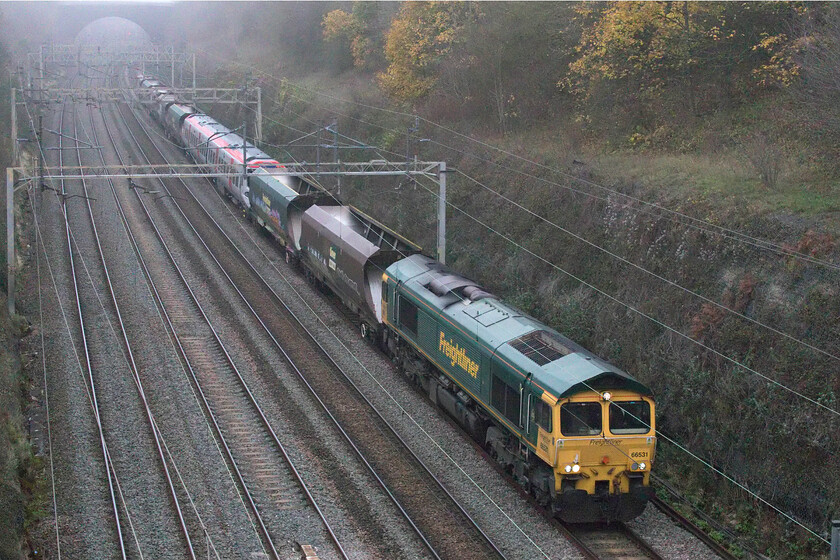 66531 & 197014, 10.35 Crewe Basford Hall-Wolverton Centre Sidings (6Q98, 32L), Hyde Road bridge 
 During the week I read in Rail 971 that the first Class 197s have entered service on the North Wales coast others are still being prepared for service prior to testing. Freightliner's 66531 tows 197014 sandwiched between some former HIA hoppers acting as barrier vehicles through Roade. I am not sure why the Class 197 was being taken to Wolverton Works from Basford Hall but I do know that the shunter will be busy on its arrival in order to extricate it from the barrier vehicles. 
 Keywords: 66531 197014 10.35 Crewe Basford Hall-Wolverton Centre Sidings 6Q98 Hyde Road bridge Freightliner TfW