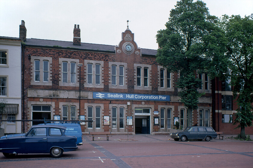 Frontage, Hull Corporation Pier booking office 
 This building is one of those that has the accolade of being one of a small handful of railway stations that are not actually located on or near a railway line! A week before its closure due to the opening of the Humber bridge, Hull Corporation Pier station is seen located opposite the waterfront with its namesake pier directly behind me. The building is a grand affair with the Manchester Sheffield and Lincolnshire (MS&L) insignia crest carved from stone contained within a trefoil above a non-working clock. Just in case Victorian travellers did not know the name of the company that was conveying them the plain stone band above the ground floor windows to which the Sealink board is attached once had the words 'Manchester, Sheffield and Lincolnshire Railway' written in relief stone stretching the full length of the building. Following closure, the building remained empty for many years but in the early 2000s, it was converted into apartments. Also notice the period cars parked at the front of the building, a blue Morris Marina van is parked behind a rather nice-looking Reliant Regal with a very tatty Mk.I Cortina on the right-hand side that doesn't look as though it is long for the roads! 
 Keywords: Frontage, Hull Corporation Pier booking office Sealink