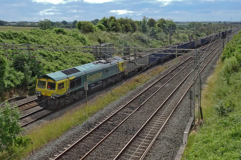 66418, 09.36 Willesden Euroterminal-New Bilton (6R93, 3L), Victoria bridge 
 Taken against the sun 66418 'Patriot-In Memory of Fallen Railway Employees' leads the 09.36 Willesden to New Bilton past Victoria bridge just south of Roade. The almost daily service carries wagon loads of spoil being removed from various HS2 sites to be deposited in a huge water-filled former quarry near Rugby. 
 Keywords: 66418 09.36 Willesden Euroterminal-New Bilton 6R93 Victoria bridge Freightliner Patriot-In Memory of Fallen Railway Employees