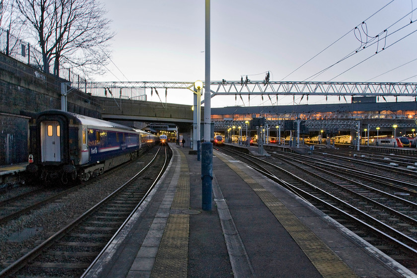 From the end of platform 1 & 2, London Euston station 
 With the sun yet to rise Euston is still bathed in artificial lighting as seen from the very end of platforms two and three. As well as the usual fare of Virgin Pendolinos to the right the Lowland sleeper has arrived at platform one and 86259 'Les Ross/Peter Pan' waits to leave with the 1Z86 07.09 charter to Carlisle, The Winter Cumbrian Mountain Express'. I really like the atmosphere evoked by the very early morning lighting giving a very chilly feel to this late February morning. 
 Keywords: From the end of platform 1 2 London Euston station