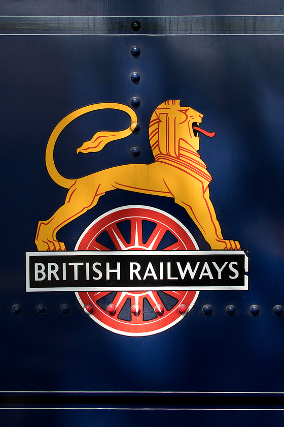 British Railway`s roundel, 6023, 12.15 Broadway-Cheltenham Racecourse, Broadway station 
 The 1948 to 1956 British Railways logo is seen reproduced on the side of the tender of 6023 'King Edward II' as it waits to leave Broadway with the 12.15 to Cheltenham Racecourse. The locomotive is painted in the original British Railways blue often referred to as ultramarine. The roundel attracted some unfortunate terms, referred to, almost others as a 'Ferret and Dartboard' and a 'Unicycling Lion'! 
 Keywords: British Railway`s roundel, 6023 12.15 Broadway-Cheltenham Racecourse Broadway station