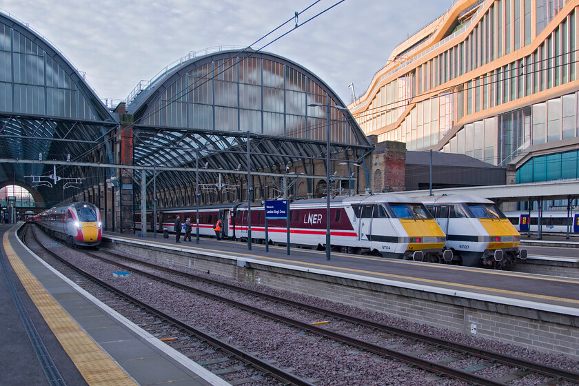 801208, GR 08.30 London King's Cross-Edinburgh Waverley (1S08, RT), 91114, GR 05.30 Leeds-London King's Cross (1A02, 9L) & 91107 , GR 08.33 London King's Cross-Leeds (1D06, 12L), London King's Cross station 
 When full Azuma operation commenced in 2020 LNER announced that a small number of the Class 225 sets would remain in operation until 2023. Writing this fast approaching the end of their target year I can find no news as to when they will be stood down even on the 225 Group's website. In the early morning light at King's Cross 91114 'Durham Cathedral' has just arrived propelling the 1A02 05.30 from Leeds and rests next to 91107 which will work the 08.33 to Leeds. Azuma 801208 is to the left and will soon leave with the 08.30 1S08 service to Edinburgh. 
 Keywords: 801208 08.30 London King's Cross-Edinburgh Waverley 1S08 91114 05.30 Leeds-London King's Cross 1A02 91107 GR 08.33 London King's Cross-Leeds 1D06 London King's Cross station LNER Azuma Durham Cathedral