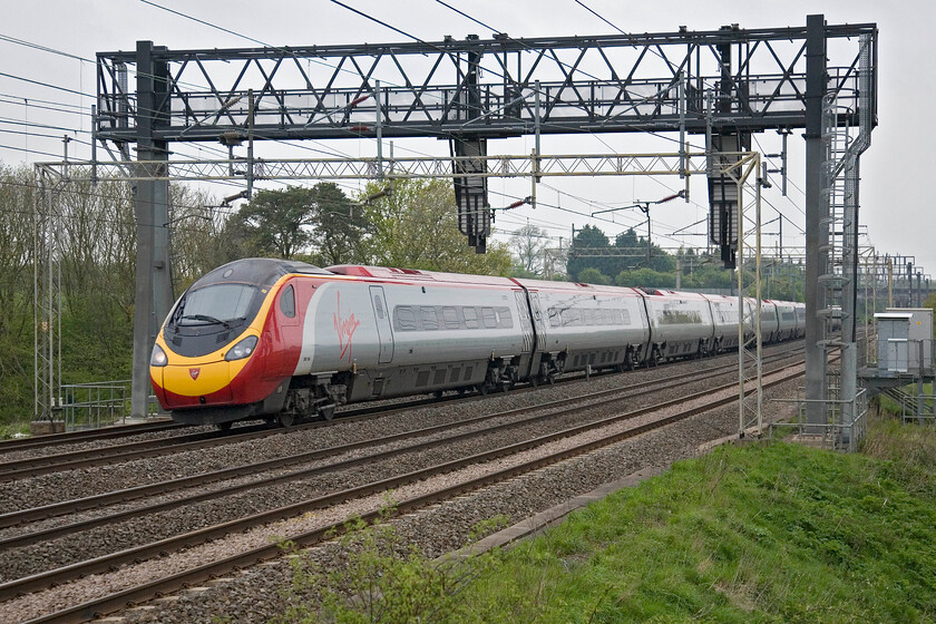 390124, VT 06.10 Manchester Piccadilly-London Euston, Roade Hill 
 Brightening up an otherwise grey and dull Saturday morning 390124 heads south working Virgin's 06.10 Manchester to Euston service. Notice that the front couple of coaches are just beginning to tilt as the train takes the right-hand curve. 
 Keywords: 390124 06.10 Manchester Piccadilly-London Euston Roade Hill Virgin Trains