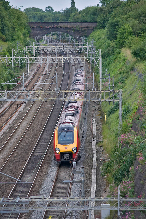 Class 221, VT 18.10 London Euston-Chester (1D32), Roade cutting 
 An unidentified Class 221 Voyager works through Roade cutting with the 18.10 Euston to Chester Virgin service. Notice in this view the up slow banner repeater signal towards the top left of the photograph. This is a digital version of the previously installed mechanical device that warns the drivers of the aspect of the signal placed out of sight around the curve near to the site of the old station. 
 Keywords: Class 221 18.10 London Euston-Chester 1D32 Roade cutting Virgin Voyager