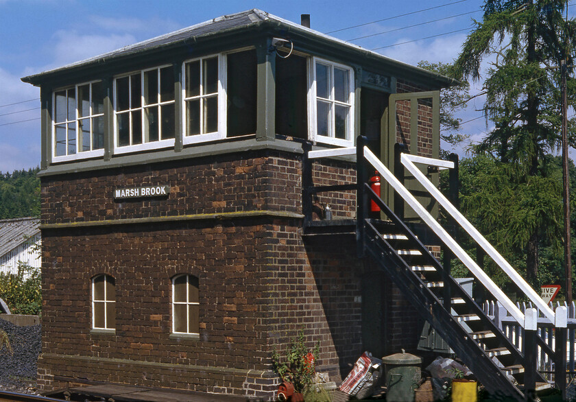 Marshbrook signal box (LNW & GW Joint, 1872) 
 Marshbrook is a tiny village nestling in the bottom of the valley just south of the Strettons. The Marches line and the A49 pass through the valley with the B4370 heading westwards towards the A489. Where the B road crosses the railway is a level crossing controlled by this superb 1872 LNW & GW Joint signal box with its pyramydal hipped roof. It is one of the oldest manual boxes in use of this type and when this photograph was taken it still controlled some mechanical gates. Notice that the wooden nameboard spells the village's name as two words but it is generally written as just one. 
 Keywords: Marshbrook signal box LNW & GW Joint 1872