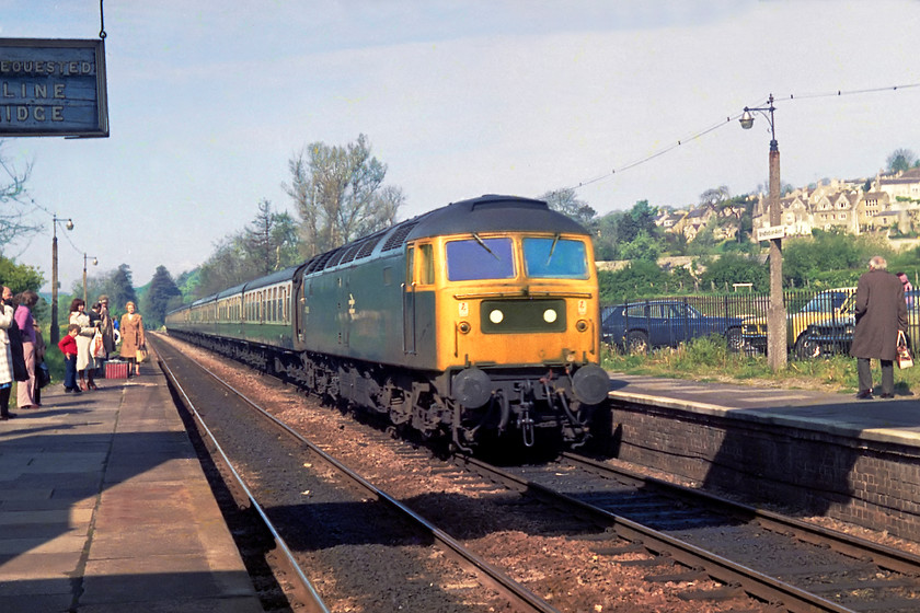 Class 47, unidentified up diversion, Bradford-on-Avon station 
 With passengers gathering the platform end colour light (BJ102) turned green. After a wait, this unidentified Class 47 passed through Bradford-on-Avon station with an unidentified working. There were GWML diversions this morning so it could have been a London Paddington working. But, that it had a uniform rake of Mk.1 stock, probably meant it was heading somewhere else, perhaps a summer Saturday special to Weymouth? Notice the ex-GWR wooden board hanging under the footbridge, I wonder where that ended up when it was removed in favour of some corporate image monstrosity? Also of note are the three cars in the adjacent car park. There's a nice Scimitar GTE (as the Princess Anne used to drive), a Morris Marina and Capri in a rather fetching shade of green! 
 Keywords: Bradford-on-Avon station class 47 Brush Type 4