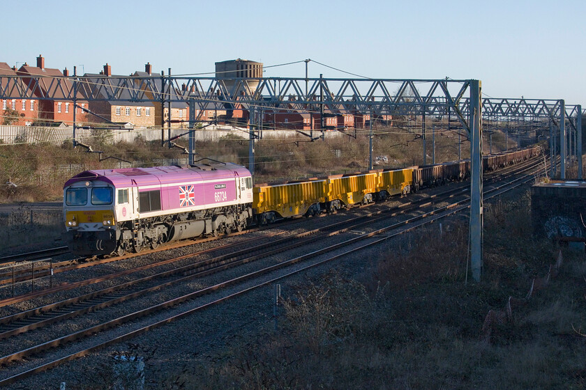 66734 & 66735, 08.05 Ledburn Junction-Bescot Yard (6G60, 316L), site of Roade station 
 How about this for a late-running engineering train? Running over an eye-watering five hours late the 6G60 08.05 Ledburn Junction to Bescot Yard used ballast train is seen passing Roade in some lovely afternoon winter sunshine. Leading the long rake of wagons is the instantly recognisable 66734 'Platinum Jubilee' with consecutively numbered 66735 'Peterborough United' just in view on the rear. I am not sure as to what held up this train (and all the others involved in the New Year's Day possession for that matter) but it certainly caused all sorts of problems on the WCML just south of Cheddington; I'd love to see the report into it! 
 Keywords: 66734 66735 08.05 Ledburn Junction-Bescot Yard 6G60 site of Roade station Platinum Jubilee