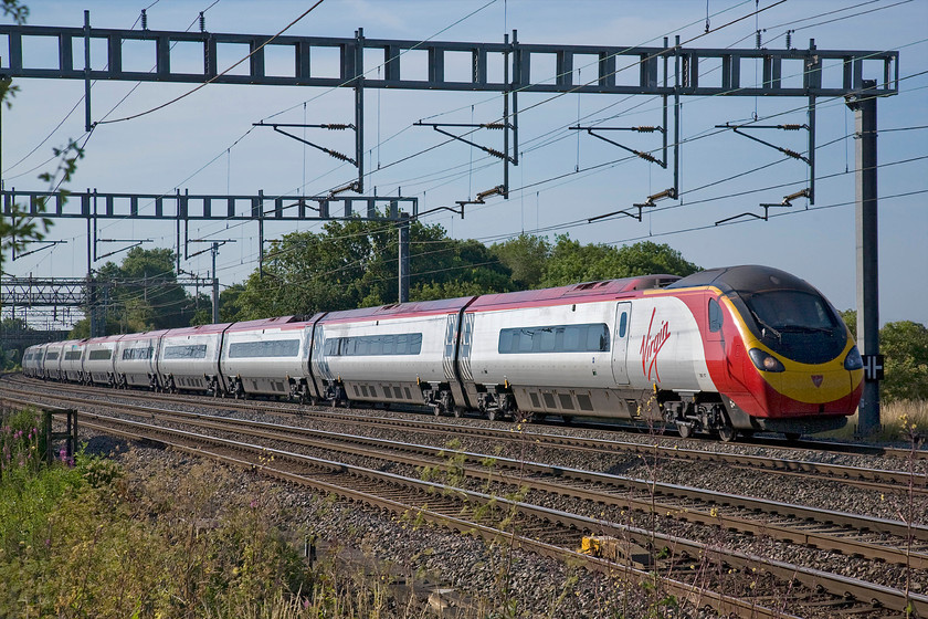 390117, VT 07.43 London Euston-Glasgow Central (9S47), Ashton Road bridge 
 390117 works the first down Anglo Scottish express of the day, the 9S47 07.43 Euston to Glasgow Central. The train is seen in lovely early morning summer sunshine passing Ashton Road bridge just south of Roade. 
 Keywords: 390117 07.43 London Euston-Glasgow Central 9S47 Ashton Road bridge Virgin Trains Pendolino