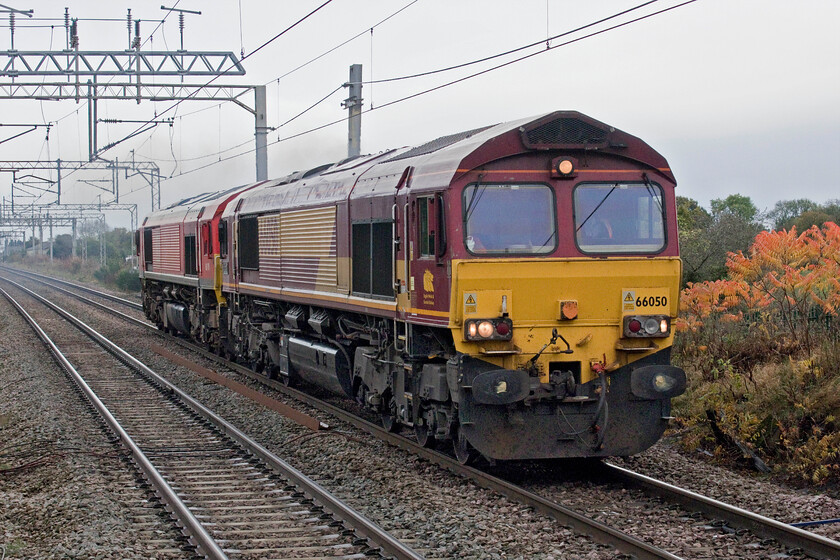 66050 & 66124, 13.45 Crewe TMD-Arpley Sidings (0Z42, 6E), Winsford station 
 With the driver of 66050 'EWS Energy' doing nothing for its fuel consumption and its emissions it accelerates extremely fast away from being held in the down loop at Winsford South Junction; perhaps the locomotive's name had encouraged his over-enthusiastic use of the power handle? The cloud of exhaust trailing the pair of locomotives (66124 on the rear) was also excessive but is not particularly clear in this photograph. The pair had just left Crewe as the 13.34 light engine move to Arpley (Warrington) as 0Z42. 
 Keywords: 66050 66124 13.45 Crewe TMD-Arpley Sidings 0Z42 Winsford station EWS DB EWS Energy