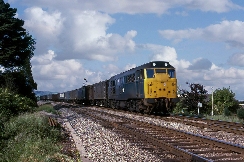 31221, down parcels, Stoke Canon 
 31221 leads a down parcels working past Stoke Canon. I am not sure exactly what this service would have been but judging by the white chits under the spring clips of each wagon it will have been a loaded train. The consist has the usual collection of mixed stock including some BR GUVs and Mk.I BG but of particular note is the number of ex-Southern four-wheel PMVs. 
 Keywords: 31221 down parcels Stoke Canon