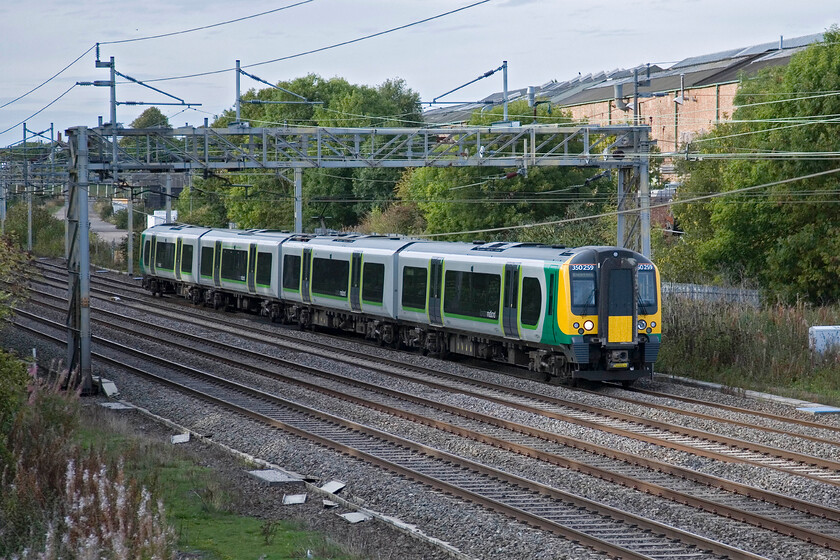 350259, LM 15.54 Birmingham New Street-London Euston, Roade 
 The 15.54 Birmingham New Street to Euston London Midland service passes Roade worked by 350259. The large structure behind the train is the now-disused Pianoforte factory that was once rail-connected. There are plans afoot to redevelop the site and turn it into a huge new housing development; something the village will no doubt be opposed to! 
 Keywords: 350259 15.54 Birmingham New Street-London Euston Roade London Midland Desiro