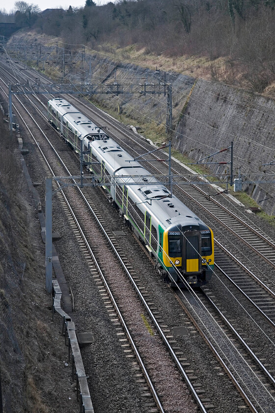 350265, LM 08.53 London Euston-Northampton, Roade cutting 
 For a Sunday morning a service such as the 08.53 Euston to Northampton a single four-car set is quite sufficient with very few passengers probably aboard. 350265 works the London Midland service through Roade cutting close to its destination. 
 Keywords: 350265 08.53 London Euston-Northampton Roade cutting London Midland Desiro