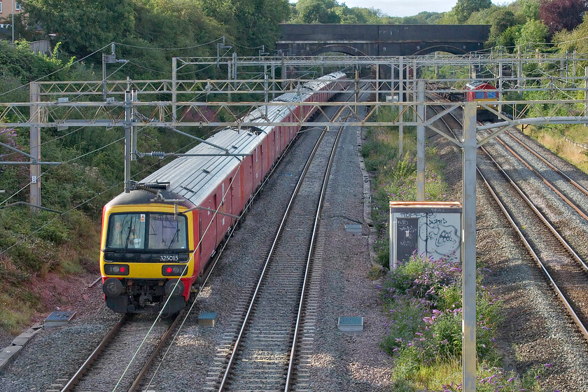 325015, 16.16 Willesden PRDC-Warrington Royal Mail (1M96, 11L) & 66182, 13.20 Trafford Park-London Gateway (4L56, 6E), site of Roade station 
 The small fleet of fifteen DB Cargo-operated Class 325s still does sterling work on the WC ad ECMLs keeping many HGV movements off the packed motorways. The rear of the 1M16 16.16 Willesden Park Royal to Warrington Royal Mail is seen passing Roade with 325015 bringing up the rear with two unidentified units up at the front. As it heads north 66182 is just coming into view leading the 13.20 Trafford Park to London Gateway service. 
 Keywords: 325015 16.16 Willesden PRDC-Warrington Royal Mail 1M96 66182 13.20 Trafford Park-London Gateway 4L56 site of Roade station Royal Mail