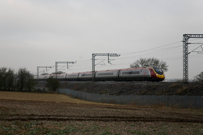 390151, VT 07.05 Wolverhampton-London Euston (1B05), Blisworth 
 390151 'Virgin Ambassador' leans into the camber on the curve at Blisworth on the Weedon loop line working the 07.05 Wolverhampton to London Euston. Illustrating how dark this February morning, the headlights of the Pendolino shine brightly through the February gloom! 
 Keywords: 390151 07.05 Wolverhampton-London Euston 1B05 Blisworth