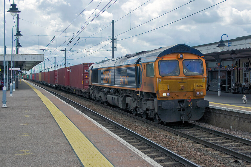 66767, 10.46 Felixstowe North-Hams Hall (4M33, 7L), Ely station 
 The final train of our short half-day trip into the Fens runs through Ely station. GBRf's 66767 'King's Cross PSB 1971-2021' leads the 4M33 10.46 Felixstowe North to Hams Hall service. Notice the small dog (on a lead I hasten to add) to the right of the photograph that was running towards and barking at the freight as he was to every train passing, indeed he is seen in an image a few photographs previously! Despite him being on a lead, it is not really the done thing on a busy station for both railway staff and other passengers to have to put up with is it really? 
 Keywords: 66767 10.46 Felixstowe North-Hams Hall 4M33 Ely station King's Cross PSB 1971-2021 GBRf