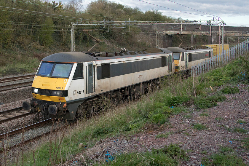 90013 & 90007, 21.34 Coatbridge-Felixstowe North (4L89, RT), Ashton Road bridge 
 Not a great photograph but this was not where I had intended to take it. The higher speed of AC powered Freightliner services caught me out as I had intended to be further on but heard the train emerging out of Roade cutting before I had reached my intended spot! Former Greater Anglia 90013 and 90007 'Sir John Betjeman' lead the 4L89 21.34 Coatbridge to Felixstowe Freightliner service seen emerging from the Ashton to Roade bridge in Northamptonshire. It is interesting to note that Freightliner has chosen to keep the names of some of their recently aquired GA electric locomotives that are not specific to their former operating area. 
 Keywords: 90013 90007 21.34 Coatbridge-Felixstowe North 4L89 Ashton Road bridge Freightliner Greater Anglia Sir John Betjeman