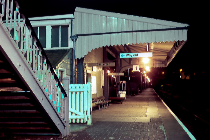 Platform 1 (down), Totnes station 
 Wreaking of the former GWR, Totnes' down platform 1 is seen in the dark on this chilly September night. Yes, I know that there are fluorescent lights, modern benches and BR corporate image signage but is heritage is unmistakable. There were once more buildings on this, the down platform, but they were destroyed by a Luftwaffe air-raid in October 1942. In addition, the original footbridge seen here to the left of the [photgraph was destroyed by a crane involved in track renewals in 1987 to be replaced by a modern example that itself was removed in 2019 to be replaced by one that has lifts and is fully compliant with accessibility legislation. 
 Keywords: Platform 1 down Totnes station