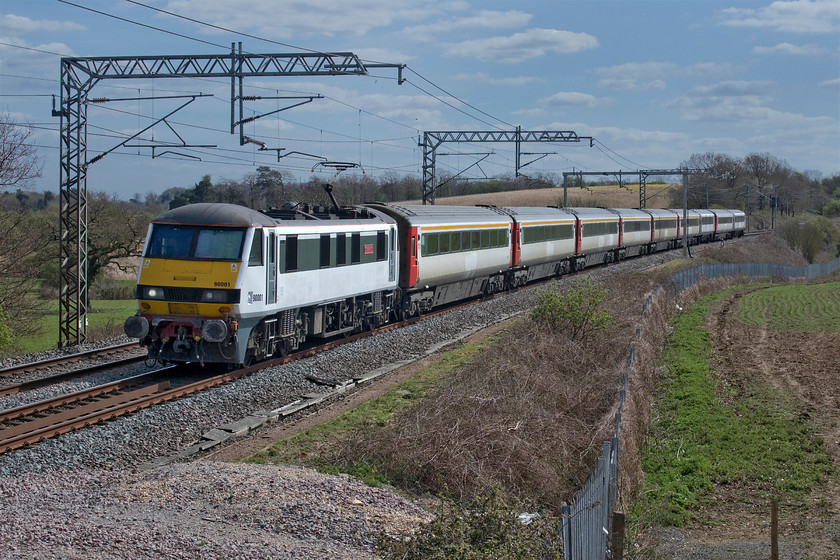 90001, 82127 & 82118, 08.42 Norwich Crown Point-Crewe HS (5Z90, 68E), Milton Crossing 
 Looking as though it's had a bit of a spruce up, 90001 'Crown Point' leads the 5Z90 08.42 Norwich Crown Point to Crewe past Milton crossing between Roade and Blisworth in Northamptonshire. This is a repeat run of yesterday's train, see..... https://www.ontheupfast.com/p/21936chg/28963065804/x90002-08-42-norwich-crown-point but the location and lighting today is much improved. As per yesterday, the train is formed of redundant Greater Anglia assets that have been disposed of to Locomotive Services Ltd. They are making their way to Crewe for further use or, in the case of the stock, probably scrapping. Having expressed surprise that yesterday's locomotive retained its nameplates, I am even more surprised that 90001 retains its 'Crown Point' plates. Having been the place that 90001 has spent its last fifteen years or so I thought that staff there would have removed them and apply them to a wall in the depot before LSL took the locomotive? 
 Keywords: 90001 82127 82118 08.42 Norwich Crown Point-Crewe HS 5Z90 Milton Crossing Greater Anglia Locomotive Services Ltd DVT Mk. III Mark 3 Crown Point