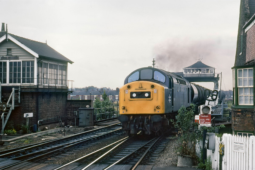 40199, up oil tankers, Selby station & signal box 
 40199 comes over the Selby swing bridge with an up tanker train. It will take the centre road through the station as it heads south. The closed Selby North signal box is seen to the left of the image devoid of its namaplate. I remember the very distinctive noise of trains crossing the swing bridge, the 'click-clack' of the wheels over extra large joints where the swing bridge separated from the land was very loud. The swing bridge was another factor that lead to the opening of the Selby diversion in 1983 as it created a bottleneck that compromised ECML timings. 
 Keywords: 40199 up oil tankers Selby station signal box