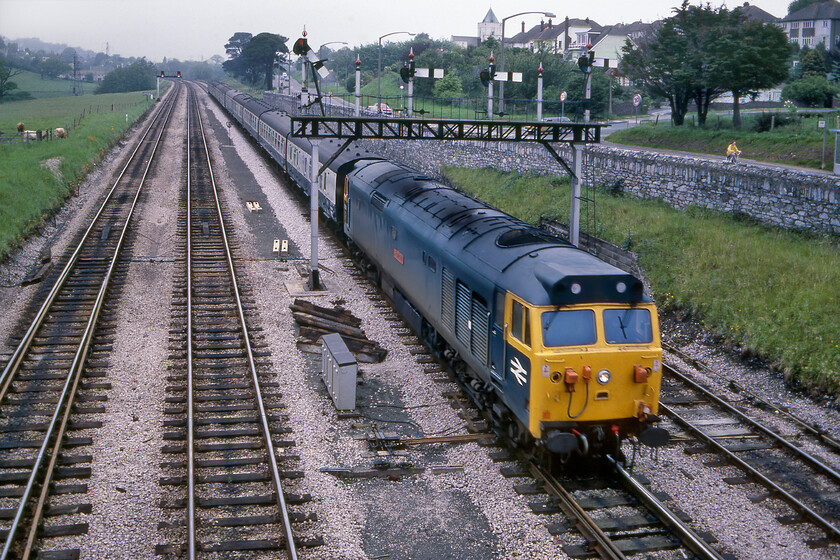 50017, 10.23 Manchester Piccadilly-Plymouth (1V82), Aller Junction 
 This image of 50017 'Royal Oak' is a little spoilt by some motion blur but presents an impressive sight as it passes under Aller Junction's six doll (with four still in use) down gantry. The Class 50 was leading the 10.23 Manchester to Plymouth 1V82 service that the girl on the bike riding along the adjacent A380 appears to be racing! 50017 was the third member of the class to be refurbished at Doncaster re-entering service on 05.02.80. 
 Keywords: 50017 10.23 Manchester Piccadilly-Plymouth 1V82 Aller Junction Hoover Royal Oak