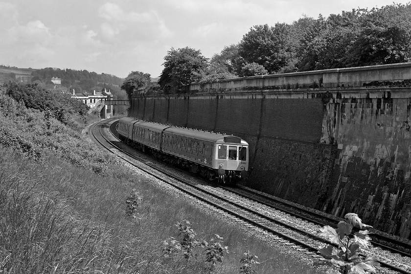 B462, unidentified Weymouth-Bristol Temple Meads working, Beckford Gardens ST758654 
 With the front end just catching the summer sunshine, a class 118 DMU set B462 approaches Bath from the east with an unidentified Weymouth to Bristol Temple Meads working. Behind the trees above the huge stone and brick retaining wall is the Kennet and Avon Canal. Notice in the background the derelict houses of Hampton Row, a scene that has blighted this part of the beautiful city of Bath for many years. Quite why nobody has been able to grasp the nettle and re-develop these houses and turn them back into the fine properties that they once were and that are worthy of the Bath is beyond me! 
 Keywords: B462 Weymouth-Bristol Temple Meads working Beckford Gardens ST758654