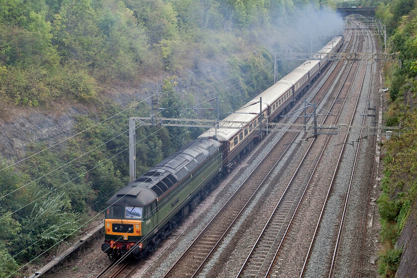 D1935, 09.05 Crewe HS-Southall LSL (5Z47, 18L), Roade cutting 
 With the exhaust from 34046 'Braunton' filling Roade cutting it climbs away heading south leading the 5Z47 09.05 Crewe HS to Southall LSL empty stock move. Appearing to be switched off at the rear of the train D1935 'Roger Hosking MA 1925-2013 appears to going along for the ride! Roger Hosking was a notable expert and writer on the history of both railway and maritime postage. He was also the father of the somewhat controversial figure of Jeremy Hosking who as a railway entrepreneur has become an important figure within the industry. However, he has also set himself up as the darling of the right-wing libertarian movement and has donated much money to various causes such as Farage's Brexit Party and to former actor Laurence Fox's Reclaim Party to support his failed bid to become London mayor in 2021. 
 Keywords: Roger Hosking MA 1925-2013 D1935, 09.05 Crewe HS-Southall LSL 5Z47 Roade cutting