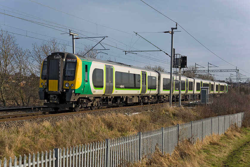 350232, LM 11.25 Northampton-Birmingham New Street, Wilson's Crossing 
 The installation of palisade fencing at this location a few years ago really spoilt the view from a photographic perspective but as time and plant growth have progressed they have softened the scene a little. 350232 climbs away from Northampton at Wilson's Crossing working the local 11.25 Northampton to Birmingham New Street stopper service. 
 Keywords: 350232 11.25 Northampton-Birmingham New Street Wilson's Crossing London Midland Desiro