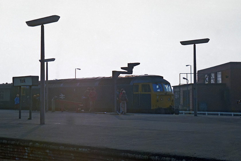 Class 47, unidentified down working, York station 
 Looking directly into the afternoon sun a class 47 leaves York station with an unidentified down working. A few spotters are there to witness the scene and collect the number, as I did on the day. The problem is, I have lost my notes form this day at York so I have no record of what this engine was!