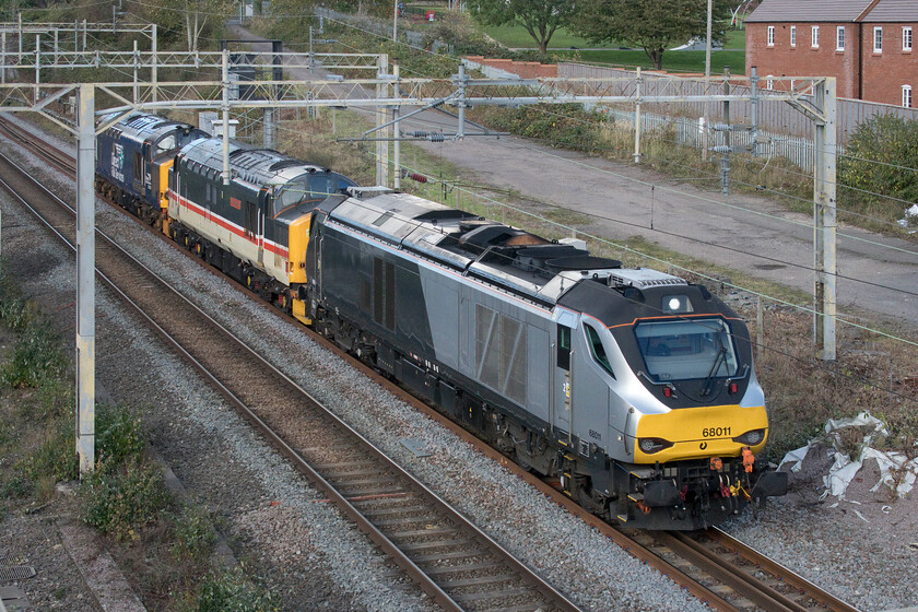 68011, 37419 & 37423, 10.16 Crewe Gresty Bridge-Willesden Yard (0Z19, 14L), site of Roade station 
 An interesting trio of locomotives heads south past the site of Roade's former station. The more modern 68011 leads and provides the power towing 37419 'Carl Haviland 1954-2012' with 37423 'Spirit of the lakes' at the rear. With DRS set to dispose of virtually all of its 'classic' locomotives with them being put up for tender, it is likely that they will soon be a memory for us enthusiasts with the sounds of English Electric engines to be lost. 
 Keywords: 68011 37419 37423 10.16 Crewe Gresty Bridge-Willesden Yard (0Z19, 14L), site of Roade station Carl Haviland 1954-2012 Spirit of the lakes