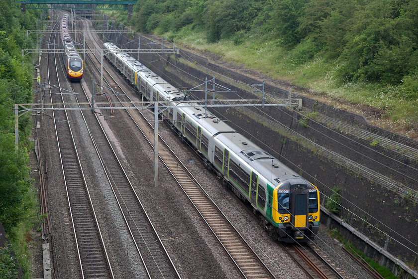 350368 & 350233, LN 15.14 Birmingham New Street-London Euston (1Y58, RT) & 390135, VT 12.40 Glasgow Central-London Euston (1M13, 4E), Roade Cutting 
 London Northwestern versus Virgin in Roade Cutting! On the up slow, 350368 and 350233 pass working the 1Y50 15.14 Birmingham New Street to London Euston. Meanwhile, 390135 'City of Lancaster' is about to overtake it on the up fast with the 1M13 12.40 Glasgow Central to London Euston. 
 Keywords: 350368 350233 1Y58 390135 1M13 Roade Cutting